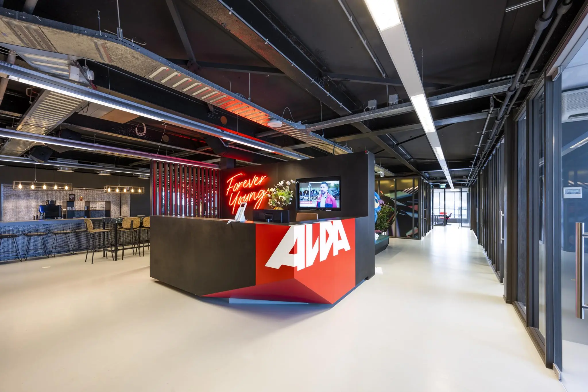 Moderne receptiebalie van AWA aan de Anthony Fokkerweg met neontekst "Forever Young" en een industrieel interieur.